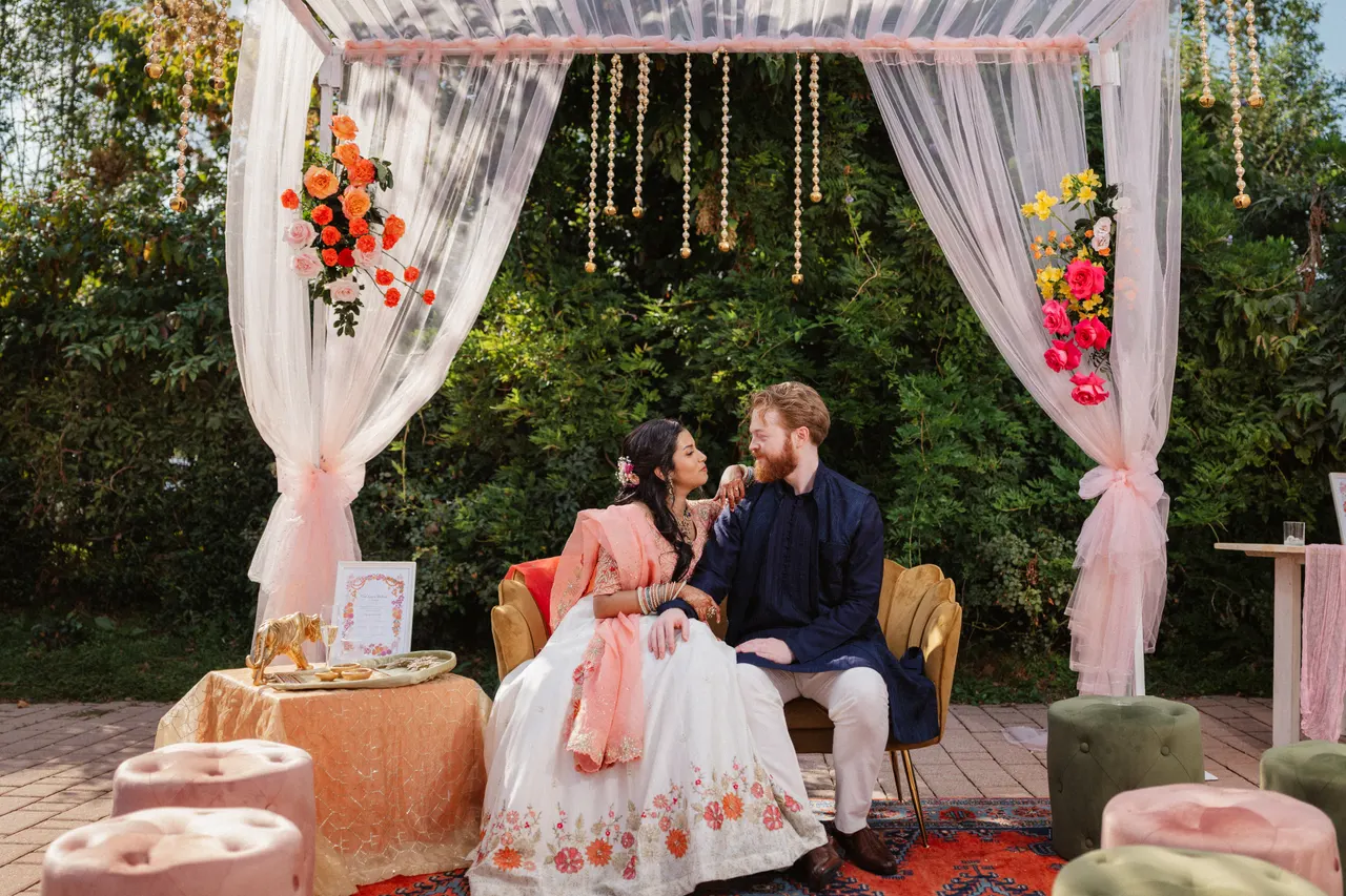 Sara and Leo seated together under the haldi canopy.