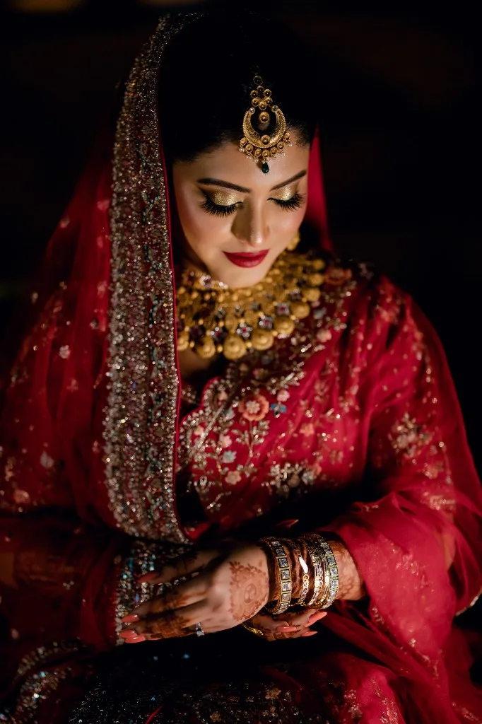 Sara in red and gold, looking down at her henna and bangles.