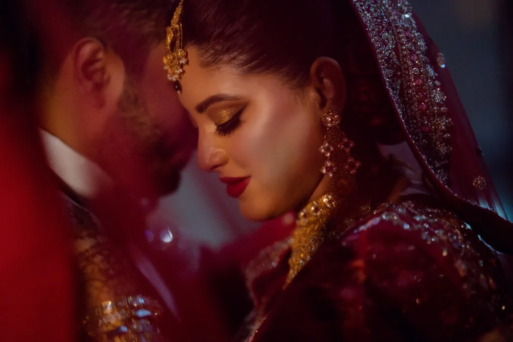 Sara in red and gold, head bowed, with Leo beside her.