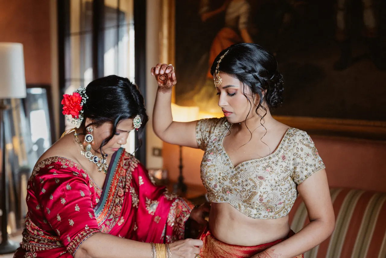 Sara getting ready, her mother fastening the sari.